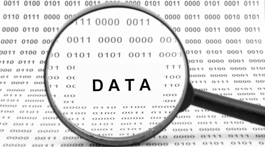 A magnifying glass zooms in on the word “DATA” against a background of binary code (0s and 1s). 