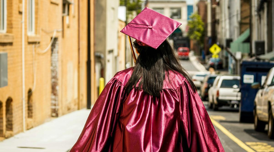 Female student in graduation robes from the back
